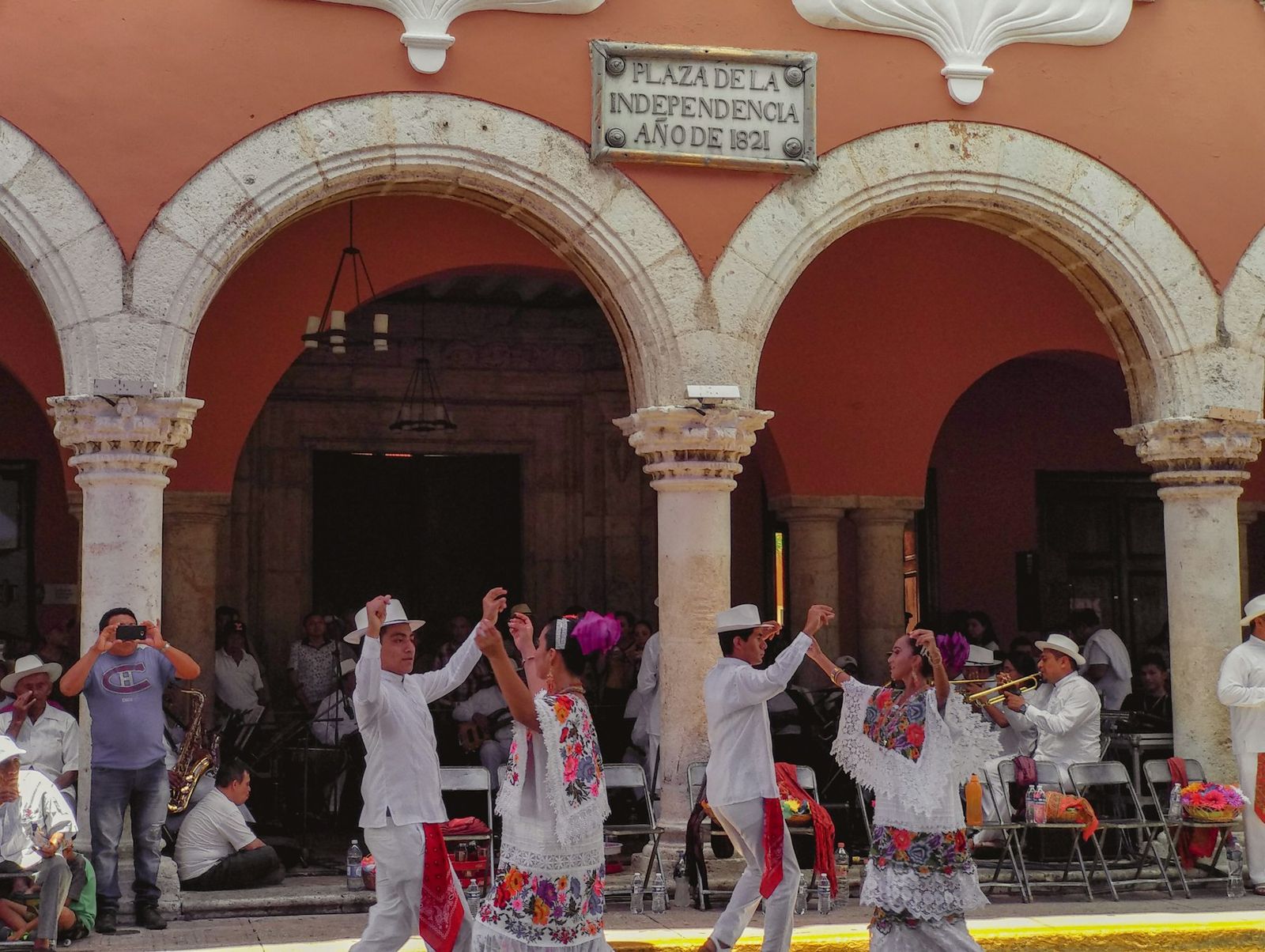 Bailarines de jarana bajo los arcos de un edificio colonial